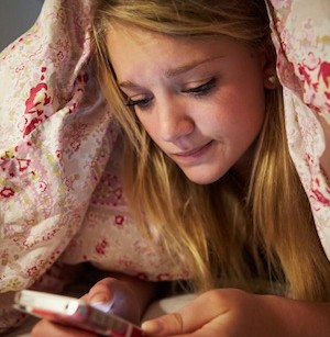 Unhappy Teenage Girl Sending Text Message Whilst Lying In Bed