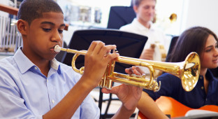 Male Pupil Playing Trumpet In High School Orchestra