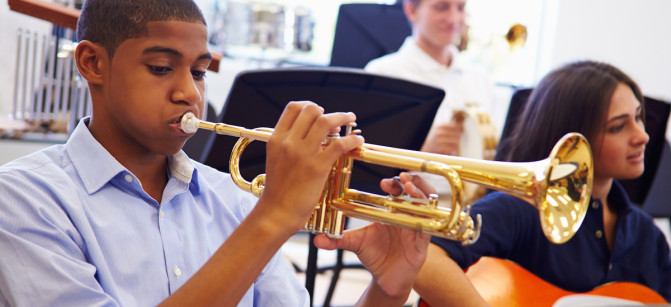 Male Pupil Playing Trumpet In High School Orchestra