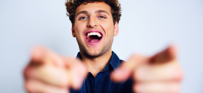 Portrait of a laughing man pointing at you