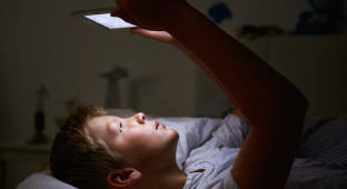 Boy Looking At Digital Tablet In Bed At Night