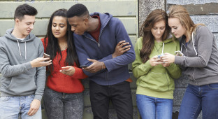 Group Of Teenagers Sharing Text Message On Mobile Phones