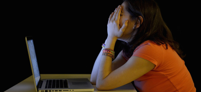 Young student woman alone at desk with computer crying desperate suffering