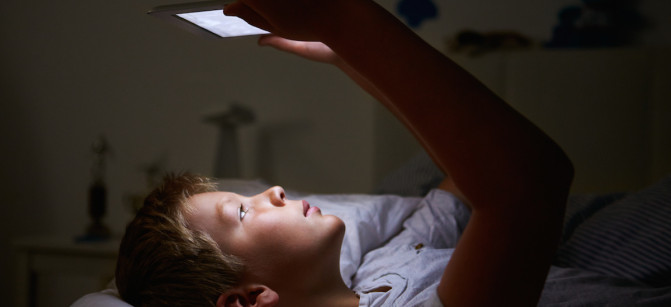 Boy Looking At Digital Tablet In Bed At Night