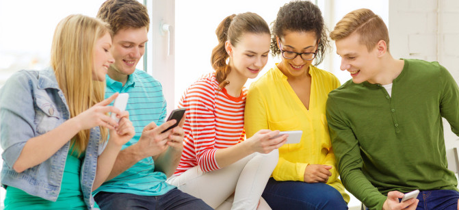 smiling students with smartphone texting at school