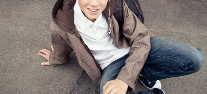 School teen sits on skateboard near school