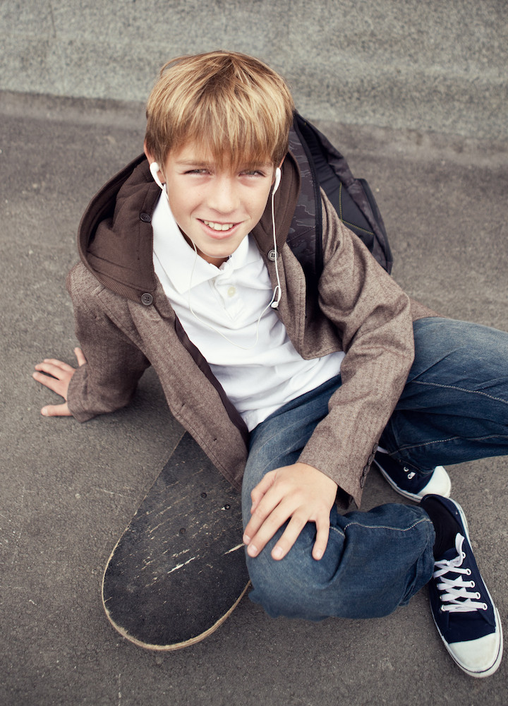 School teen sits on skateboard near school