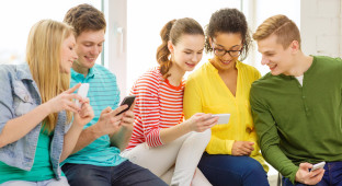 smiling students with smartphone texting at school