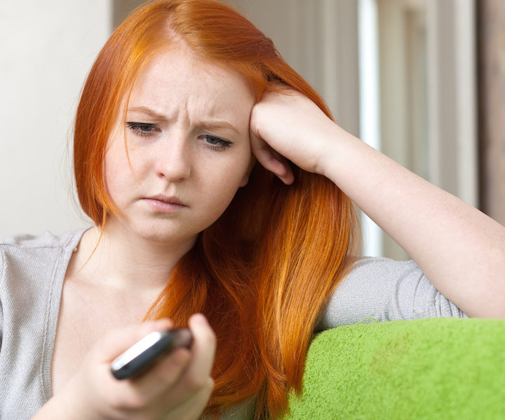 Red-haired  teenager girl  having disappointment  after phone call