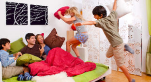 a young family is making a pillow-fight in their bedroom