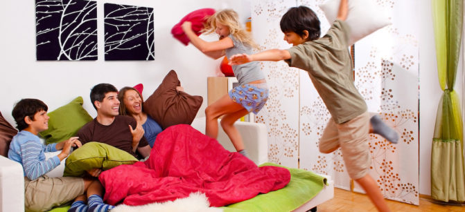 a young family is making a pillow-fight in their bedroom