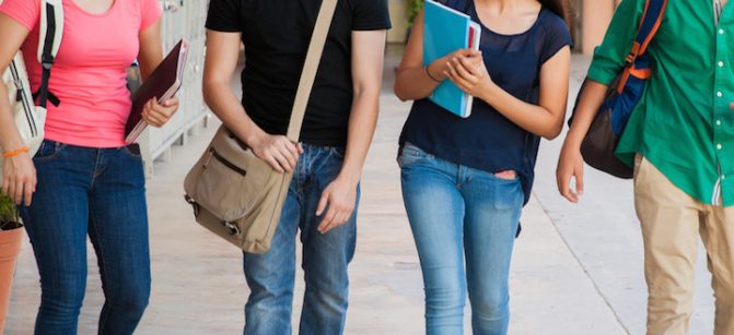 Group of high school students talking and laughing in a hallway between classes