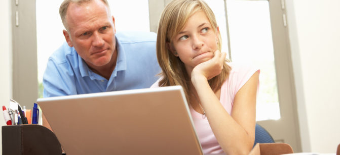 Angry Father And Teenage Daughter Using Laptop At Home