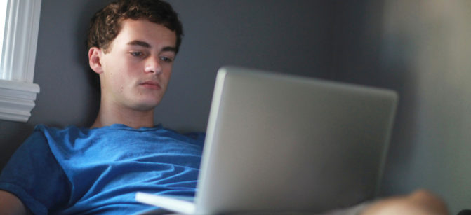 Teenage boy in room using laptop