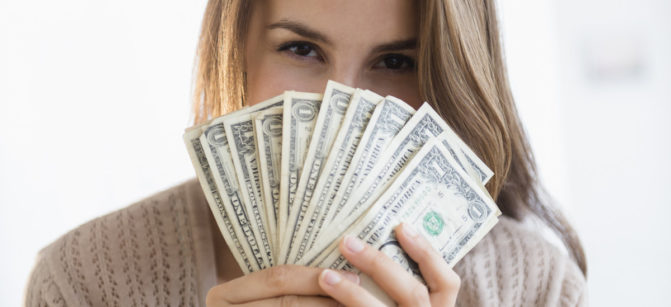 Woman peeking behind money