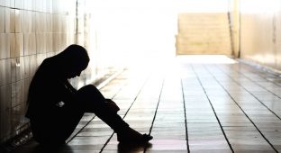Backlight of a teenager depressed sitting inside a dirty tunnel