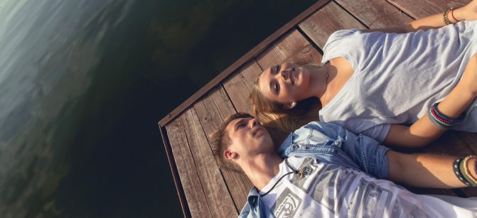 Young Couple Relaxing Near River Enjoying Sunny Day