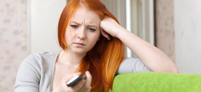 Red-haired  teenager girl  having disappointment  after phone call