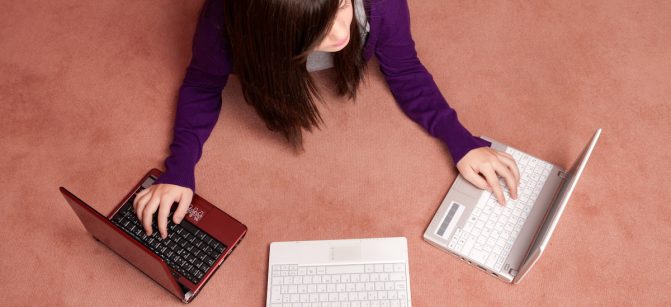 Young woman multitasking with three laptop lying on floor