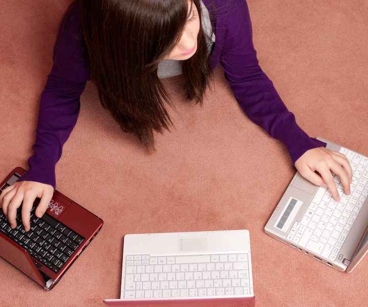 Young woman multitasking with three laptop lying on floor