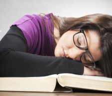 Tired female student sleeping on the big book