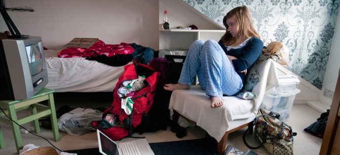 Teenaged girl watching television in messy bedroom