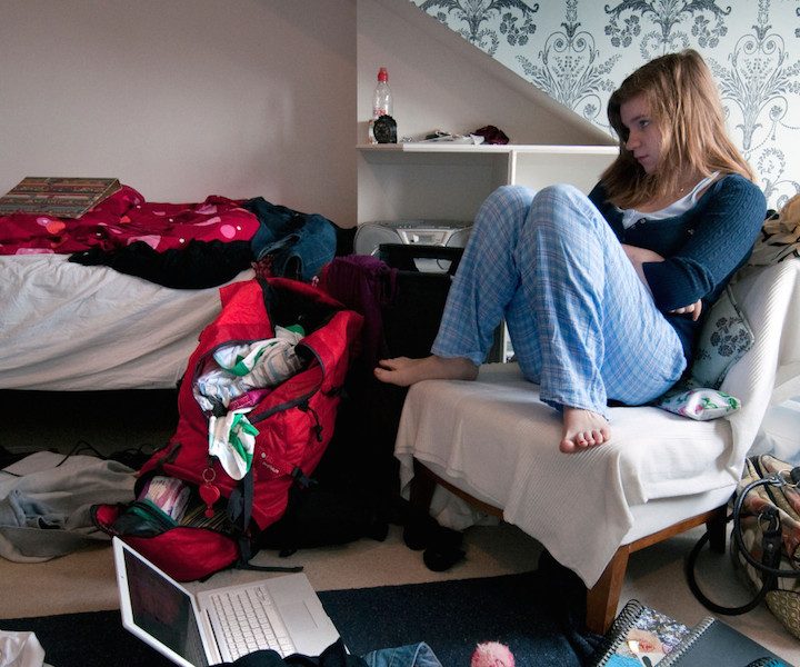 Teenaged girl watching television in messy bedroom