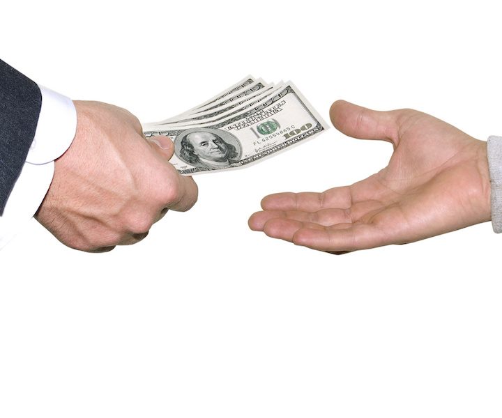 a suited hand handing some money to a poor looking hand
