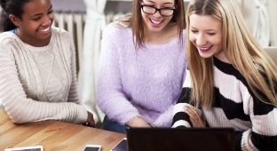 Multi ethnic young girls studying together at home, on computer