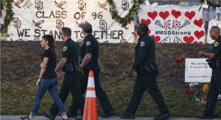 Marjory Stoneman Douglas High School staff, teachers and students return to school greeted by police and well wishers in Parkland, Florida on February 28, 2018. 
Students grieving for slain classmates prepared for an emotional return Wednesday to their Florida high school, where a mass shooting shocked the nation and led teen survivors to spur a growing movement to tighten America's gun laws. The community of Parkland, Florida, where residents were plunged into tragedy two weeks ago, steeled itself for the resumption of classes at Marjory Stoneman Douglas High School, where nearby flower-draped memorials and 17 white crosses pay tribute to the 14 students and three staff members who were murdered by a former student.
 / AFP PHOTO / RHONA WISE        (Photo credit should read RHONA WISE/AFP/Getty Images)