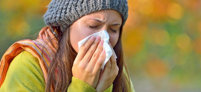 Girl in fall autumn park sneezing in t