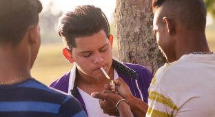 Youth culture, young people, group of male friends, mixed race teen outdoor, teenager in park. Hispanic kid smoking cigarette, confident boy, smoker. Health problems, social issues. Cigarettes
