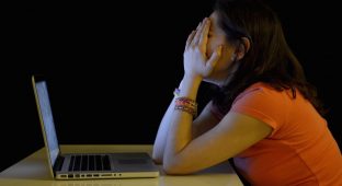Young student woman alone at desk with computer crying desperate suffering cyber mobbing and bullying