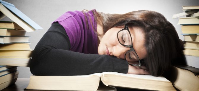 Tired female student sleeping on the big book