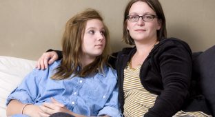 Mother and daughter sitting in sofa. Mother has an absent look