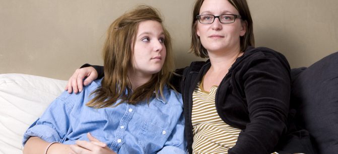 Mother and daughter sitting in sofa. Mother has an absent look