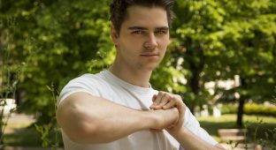 Attractive confident young man in nature environment holding fist with other hand