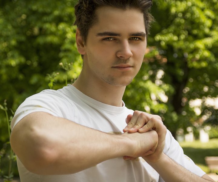 Attractive confident young man in nature environment holding fist with other hand