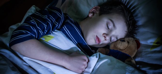 Sleeping child with his toy bear.