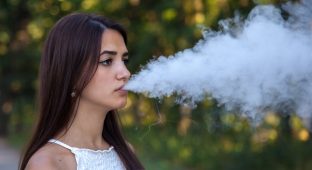 serious cute woman vaping in the park