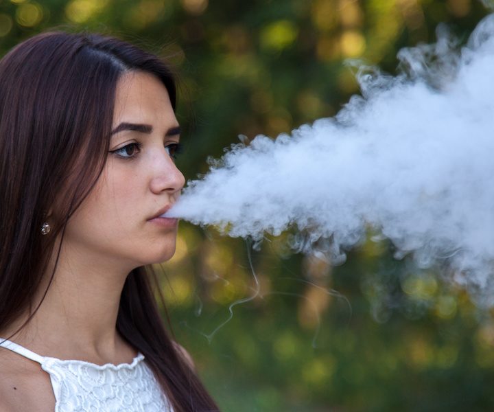 serious cute woman vaping in the park