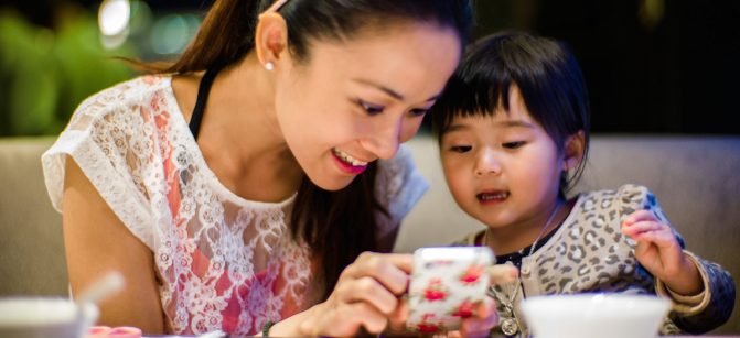 Young mom & toddler using smartphone cell parent  dinner