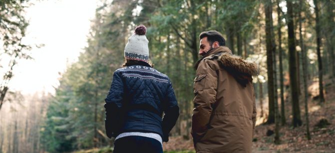 Rear view of father and son walking in autumn forest