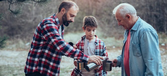 Photo of three generations males in nature drinking warm tea.