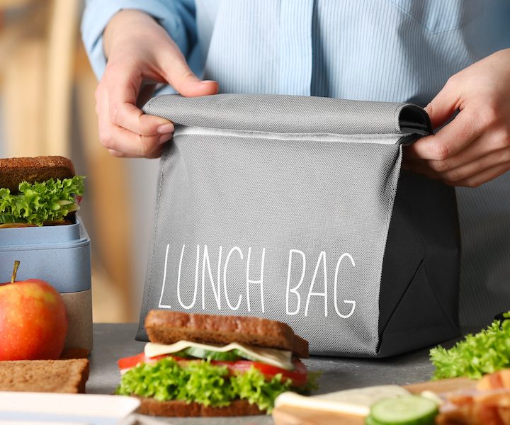 Mother packing meal for school lunch on table