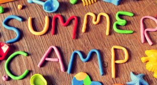 the text summer camp made from modelling clay of different colors and some beach toys such as toy shovels and sand moulds, on a rustic wooden surface